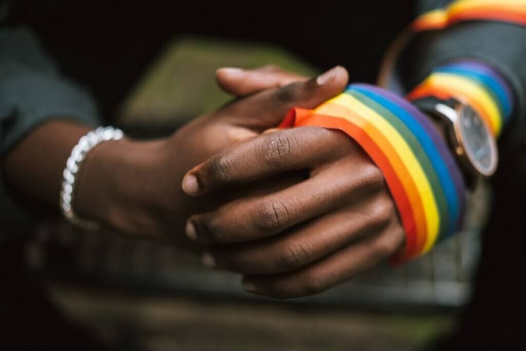 Folded hands with rainbow colored garland wrapped around wrist
