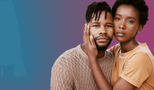 A couple is shown against a gradient background transitioning from blue to purple. The woman in a yellow shirt gently touches the face of the man in a beige sweater. Both have a serious and contemplative expression, reflecting on their health and wellness journey together.