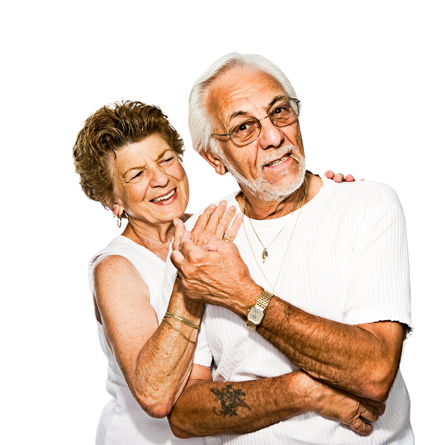 An elderly couple stands close together, smiling warmly in the heart of central Florida. The woman has short, curly hair and wears a sleeveless white top. She places her arm affectionately around the shoulders of the man, who has white hair, glasses, and a white shirt.