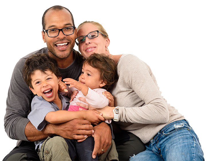 A happy family of four sits together closely, smiling and laughing. The father and mother, who are wearing glasses, look relaxed and content in their casual attire. Nestled between them, the young boy and girl giggle with joy, embodying the wellness lifestyle central to their health in Central Florida.