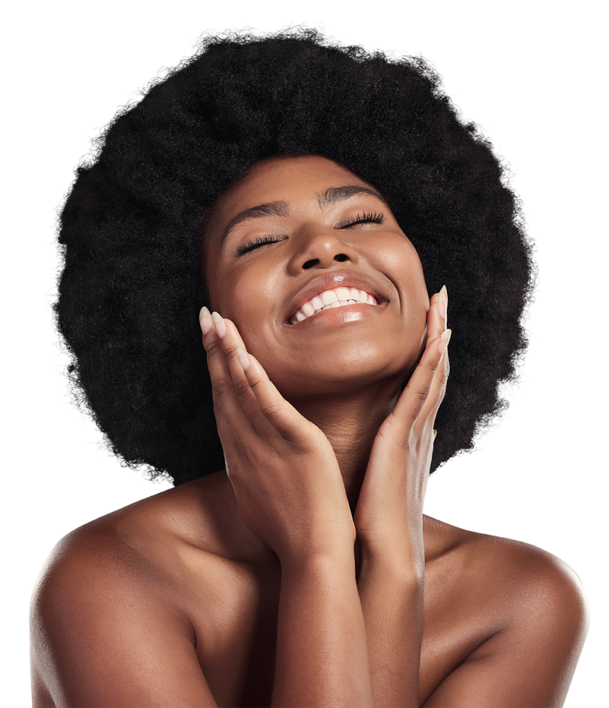 A woman with dark curly hair and bare shoulders is smiling brightly with her eyes closed. She holds her face gently with both hands in a joyful and relaxed expression. The background is white.