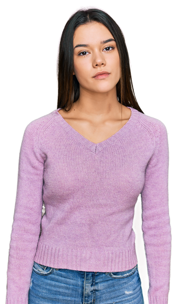 A young woman with long brown hair wearing a light purple V-neck sweater and blue jeans stands against a solid background. She has a calm, neutral expression on her face.